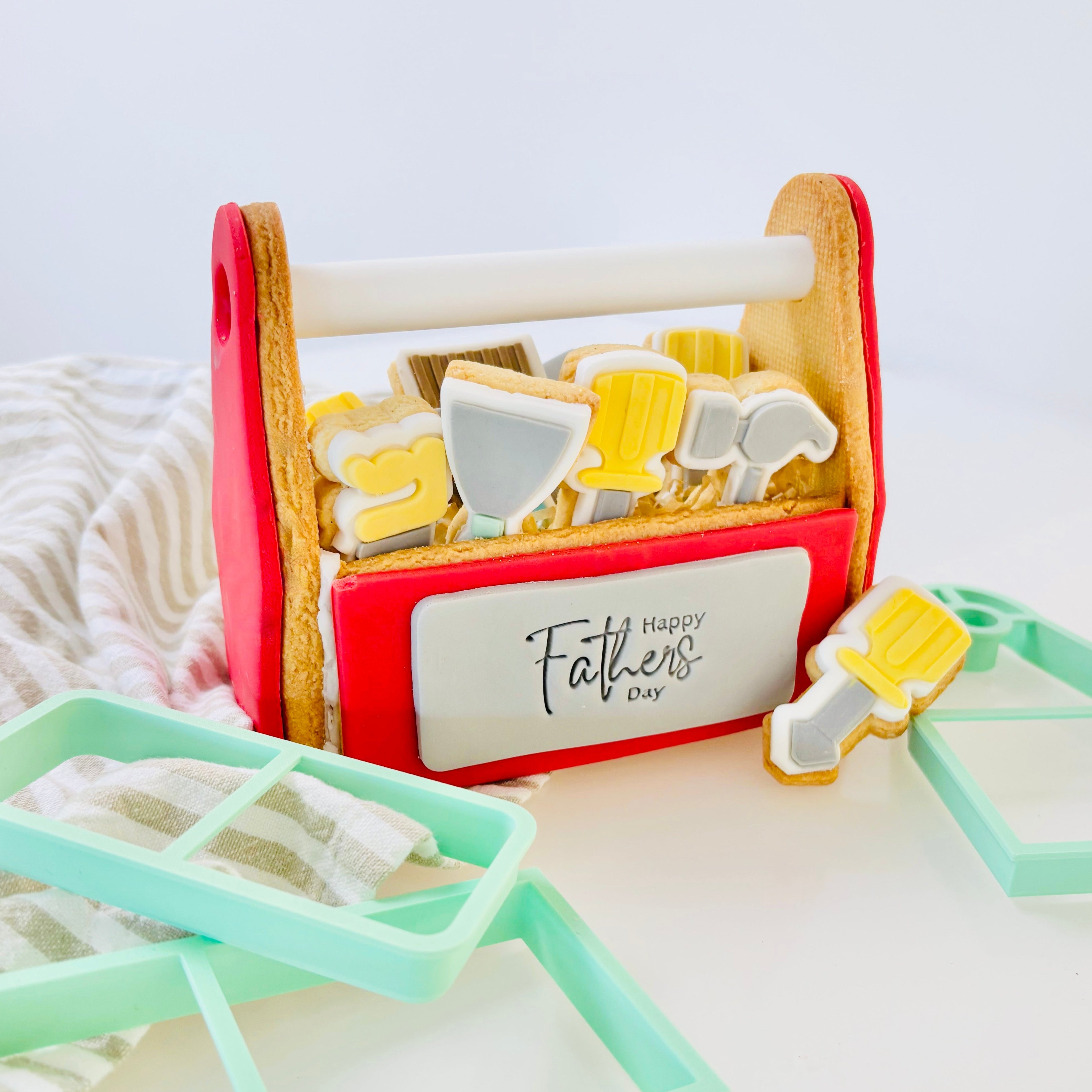 Cookie cutters in a red tool box with 'Happy Father's Day' text on a white background